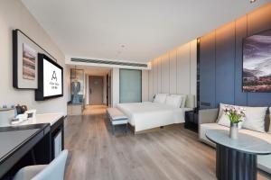 a hotel room with a white bed and a couch at Atour Hotel Kunming Changshui International Airport Cloud Cube in Kunming