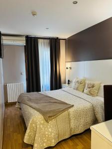 um quarto com uma cama grande e uma janela grande em Hotel El Acebo em Jaca