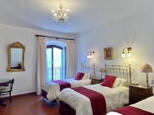 Un dormitorio con dos camas y una lámpara de araña. en El Hotel de Su Merced, en Sucre
