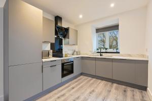 a kitchen with white cabinets and a wooden floor at Stylish Two Bedroom Apartment - Secure Parking & Balcony 9MC in Birmingham