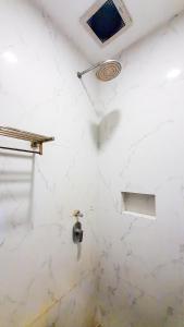 a bathroom with a white marble wall with a window at La'Rissa Residence by ARBA in Karawang +14 photos