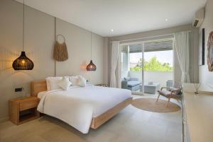 a bedroom with a large white bed and a living room at Villa Levi by GORO in Seminyak +34 photos