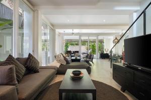 a living room with a couch and a tv at Villa Levi by GORO in Seminyak