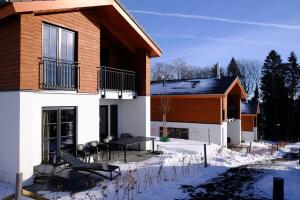 ein Haus im Schnee mit einem Tisch und Stühlen in der Unterkunft UplandParcs Winterberg in Winterberg