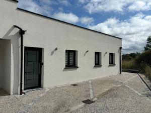 ein weißes Gebäude mit einer Tür und drei Fenstern in der Unterkunft La Vallée des Biches G1 in Saint-Martin-Boulogne
