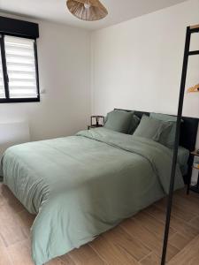 ein Schlafzimmer mit einem Bett mit einer grünen Bettdecke in der Unterkunft La Vallée des Biches G1 in Saint-Martin-Boulogne + 18 Fotos