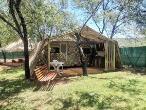 a tent with a table and a bench in front of it at Hartbeespoort Cara-glamping self-cater units in Pretoria