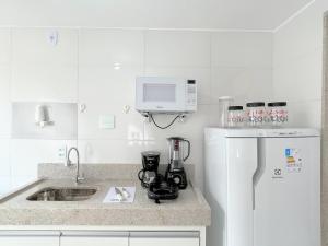 une cuisine blanche avec un évier et un micro-ondes dans l'établissement Apto Qt e sala a 100m das Castanheiras - Não fornecemos roupas de cama e banho -, à Guarapari 39 autres photos