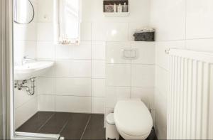 a white bathroom with a toilet and a sink at Duvenstedter Rotklinker in Hamburg