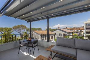 a balcony with a couch and a table and chairs at Apartments White and Green in Malinska
