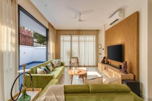 a living room with a green couch and a tv at Casa Solace 3 BHK by tisyastays in Assagao