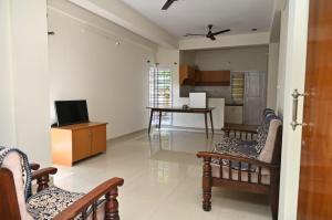 a living room with chairs and a television and a kitchen at Northern Aura in Bangalore