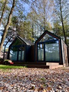 una casa negra con grandes ventanas en un montón de hojas en Leśne SPA pod Warszawą, en Wólka Radzymińska