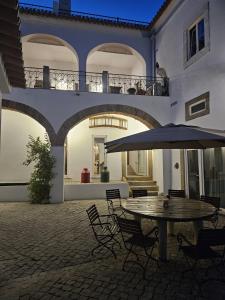a patio with a table and chairs and an umbrella at Solar de Arrayollos by PURUS in Arraiolos