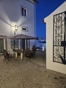 a patio with a table and chairs and an umbrella at Solar de Arrayollos by PURUS in Arraiolos
