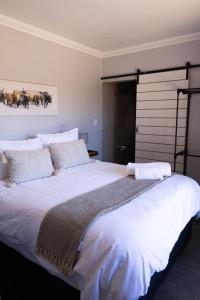 ein Schlafzimmer mit einem großen Bett mit weißen Laken und Kissen in der Unterkunft The Cottage Unit in Kathu