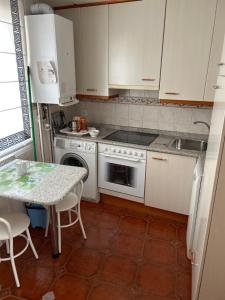 a kitchen with white appliances and a table with chairs at Mercado Chico SUITES in Avila