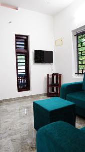 a living room with two blue couches and a flat screen tv at Prakruthi Home stay in Kanjikode