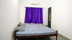 a bed in a room with a purple curtain at Prakruthi Home stay in Kanjikode