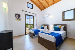 two beds in a room with a tv and a balcony at Kymma Villa #12 in Ayia Napa