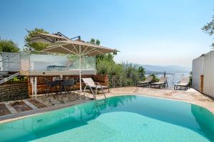 a swimming pool with an umbrella and chairs and a table at Villa Anastasia in Corfu