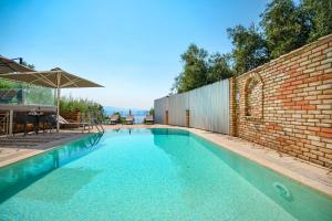 an empty swimming pool with a brick wall and an umbrella at Villa Anastasia in Corfu