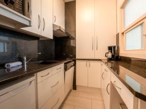 eine Küche mit weißen Schränken und schwarzen Arbeitsplatten in der Unterkunft Apartment Ravenna by Interhome in Middelkerke