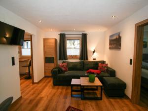 a living room with a green couch and a table at Apartment Stöckl by Interhome in Schwendau