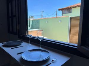 Casa aconchegante a 7 min da Praia في بوزيوس: طاولة مع طبقين وكاسات على نافذة