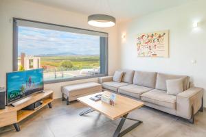 a living room with a couch and a large window at Sunset Villa in Paralia Dionysiou