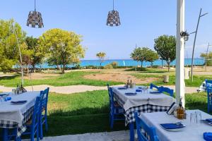 a group of tables with blue chairs and the ocean at Sunset Villa in Paralia Dionysiou