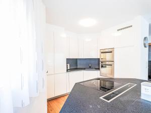 a kitchen with white cabinets and a black counter top at Apartment B21 by Interhome in Leukerbad