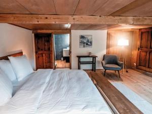 een slaapkamer met een groot bed en een stoel bij Apartment Chalet Solegg by Interhome in Innertkirchen