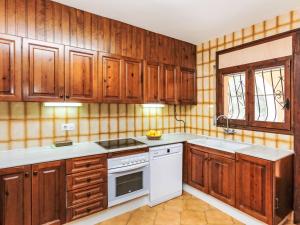 a kitchen with wooden cabinets and white appliances at Villa Africa by Interhome in L'Ametlla de Mar