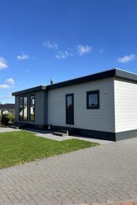 ein großes weißes und schwarzes Haus mit Auffahrt in der Unterkunft Holiday Home Noordzee Deluxe 32 by Interhome in Scherpenisse