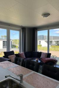 ein Wohnzimmer mit einer Couch und einigen Fenstern in der Unterkunft Holiday Home Noordzee Deluxe 32 by Interhome in Scherpenisse + 19 Fotos