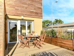 eine Terrasse mit einem Tisch und Stühlen auf einer Holzterrasse in der Unterkunft Apartment Soleil couchant by Interhome in Mimizan