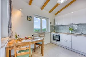 a kitchen with white cabinets and a wooden table at LOVOR - Relax in Greenery & Explore Istria in Tinjan