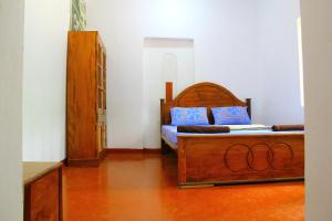 a bedroom with a wooden bed with blue pillows at Kandy Little White House in Kandy