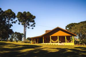 Piraí do SulにあるPousada Sitio Campina da Casaの木の前の黄色い家