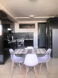 a kitchen with a table and some white chairs at Serenity at 77 Independence Avenue, Windhoek CBD in Windhoek