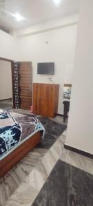 a bedroom with a bed and a flat screen tv at Rainbow Homestay Khajuraho in Khajurāho