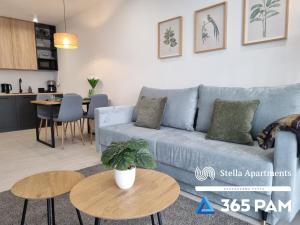 ein Wohnzimmer mit einem blauen Sofa und einem Tisch in der Unterkunft 365PAM - Resort Westin House - BASEN, JACUZZI, SAUNA, SIŁOWNIA, PLAC ZABAW W CENIE in Kołobrzeg