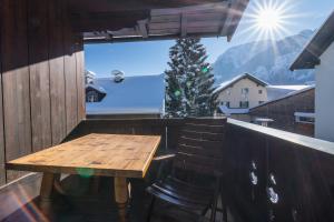 ein Balkon mit einem Holztisch und einem Weihnachtsbaum in der Unterkunft Voglstätter Appartements Lofer in Lofer