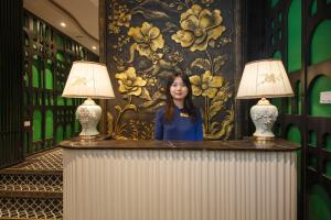 a woman standing behind a counter with two lamps at Madelise Stardust Hotel & Travel in Hanoi