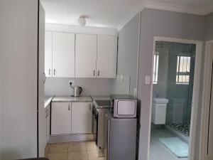 a small kitchen with white cabinets and a microwave at Daisy's Lane in East London