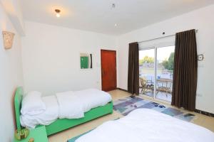 a bedroom with two beds and a balcony at Moka Gust House in Luxor