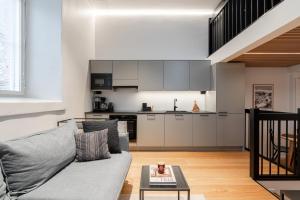 a living room with a couch and a kitchen at Stylish Loft next to City Center & Lake Pyhäjärvi in Tampere +16 photos