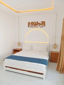 a bedroom with a white bed with a blue blanket at Double D Guesthouse and Villa in Kerobokan