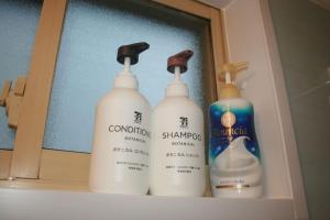 a group of three bottles of shampoo and bleach on a shelf at 駅ちか民泊金魚 in Otaru